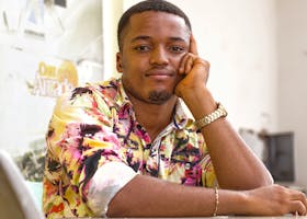 Young man wearing a colorful floral shirt, posing with a thoughtful expression indoors.